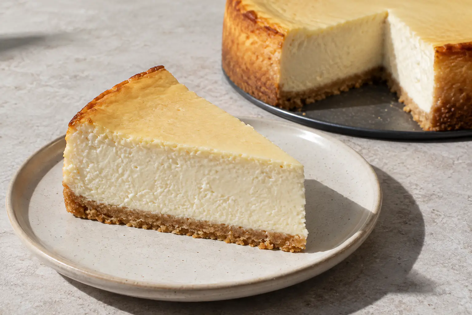 Kriška klasičnog pečenog cheesecakea s podlogom od keksa i glatkom kremom od sira
